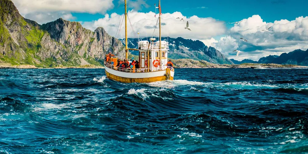 The MS Symra fishing vessel sailing past the Lofoten mountains