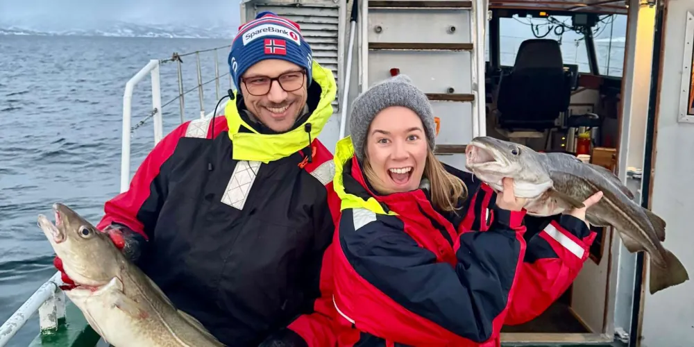 Two anglers holding cod they caught on a Tromsø fishing sea safari